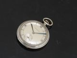 une montre de poche en argent posée sur une surface noire
