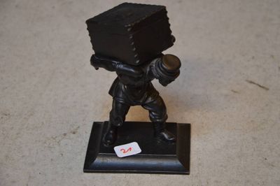 une petite statue représentant un homme avec une boîte sur la tête