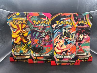 trois paquets de cartes Pokémon posés sur un canapé