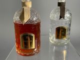 two bottles of perfume sitting on a clear shelf