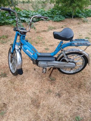 un scooter bleu garé dans l'herbe