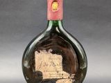 an old bottle of wine with a pink cap on a gray background