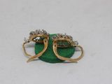 pair of gold and diamond earrings on a green cloth