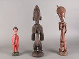 trois figurines en bois de formes et de tailles différentes posées sur une surface grise