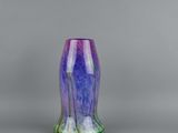 a close up of a purple and green vase on a gray surface