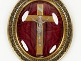 gold and red crucifix in a round frame on a red cloth