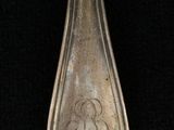 silver spoon with a design on it sitting on a black surface