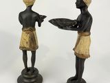 two figurines of a man and a woman holding a tray