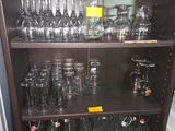 des bouteilles et des verres posés sur une étagère dans une pièce équipée d'une baignoire