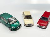 trois petites voitures assises l'une à côté de l'autre sur une surface blanche