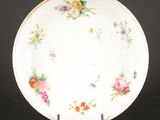 une assiette blanche décorée de fleurs, posée sur un socle