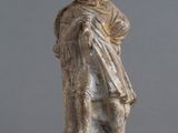 statue d'un homme portant un chapeau et une robe, sur fond gris
