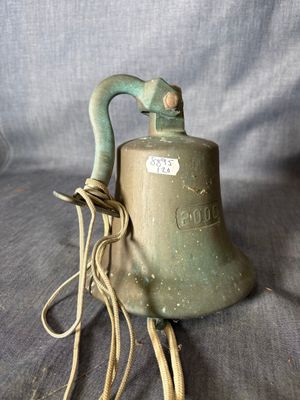 une vieille cloche, à laquelle est attachée une cordelette, posée sur un tissu bleu