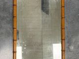 a mirror hanging on the wall with a bamboo frame