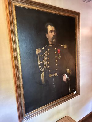 portrait of a man in a military uniform in a room with a painting on the wall