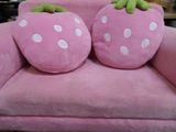 two pillows that are shaped like strawberrys on a pink chair