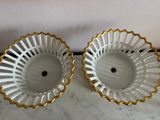 two white and gold vases sitting on top of a marble counter
