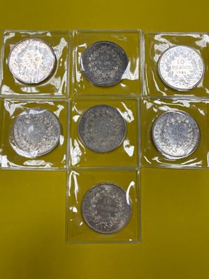 six types différents de pièces en argent dans une boîte transparente