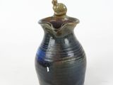 a blue and black vase with a bird on top