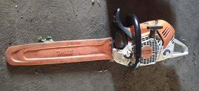 a chainsaw sitting on the ground next to a pair of scissors