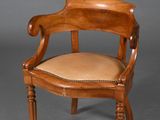 une chaise ancienne en bois, avec une assise et des accoudoirs en cuir beige