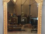 un grand miroir avec un cadre doré accroché au mur