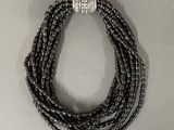 a close up of a necklace with black beads on a white surface