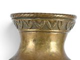 a gold vase that is sitting on a white surface
