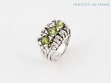 a close up of a ring with green stones on a white background