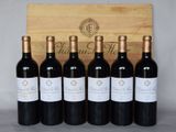 six bottles of red wine are lined up in front of a wooden box