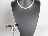 black mannequin with a white rope necklace and a wooden stand