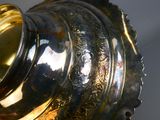 a silver vase with a gold lid sitting on a table
