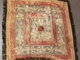un vieux tapis avec une bordure rouge et des franges, posé sur le sol