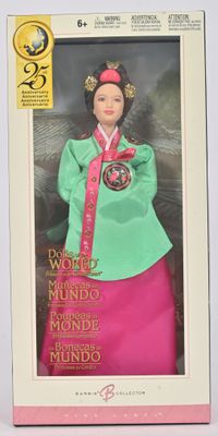 La poupée se trouve dans une boîte ; elle porte une jupe rose et un haut vert.