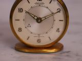 une petite horloge posée sur un plan de travail en marbre