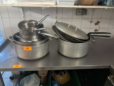 des casseroles et des poêles posées sur une étagère en acier inoxydable dans une cuisine