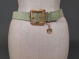 a close up of a mannequin torso wearing a green belt with a gold buckle