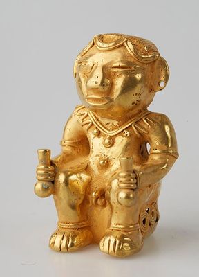 a gold figurine of a monkey sitting on a chair