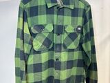 une chemise à carreaux verts et noirs suspendue à un cintre