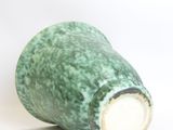 a green vase that is sitting on a white surface