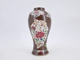 un vase marron orné de fleurs, posé sur un fond blanc