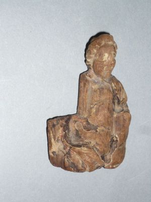 une petite statue représentant une personne assise sur un tabouret