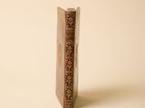 un vieux livre posé sur une table à côté d'un mur blanc
