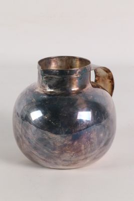 a silver vase with a brown handle on a white surface