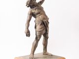 an antique bronze statue of a man holding a tennis racquet