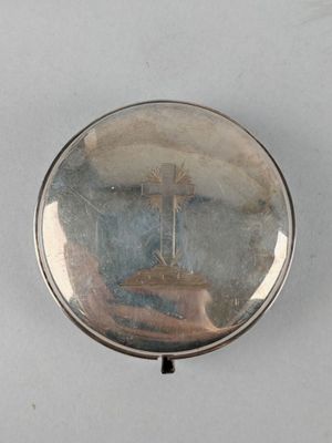un étui à pilules en argent orné d'une croix