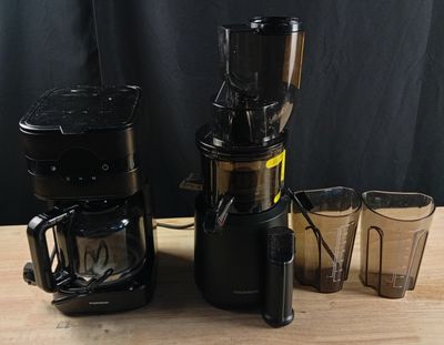 un mixeur et des tasses posés sur une table, sur fond noir