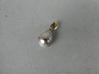 un gros plan d'un pendentif en perle blanche posé sur une surface blanche