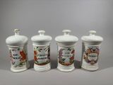 three white ceramic jars with floral designs on them sitting on a table