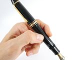 a person holding a pen in their hand on a white surface